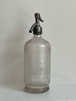 Full view of clear glass seltzer bottle with siphon head