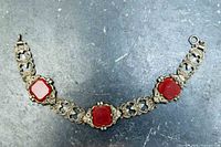 Bracelet laid flat showing filigree links and red stones