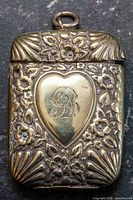 front view showing floral repoussé, heart cartouche with monogram, suspension ring