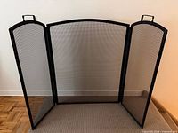 Full view of three-panel black fireplace screen fully extended