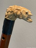Close view of carved bone dog's head handle with visible mouth damage