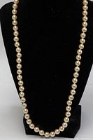 Full view of entire faux pearl necklace on display bust