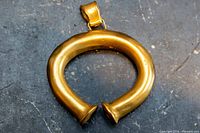 Front view of gold-tone tubular pendant showing overall shape and bail