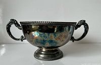 Side view of tarnished silver plated pedestal bowl with two handles