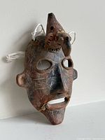 Front angled view of terracotta mask showing repairs and overall form