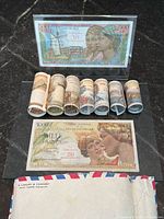 Front view 500-franc note, rolled notes in foreground, envelope and 1000-franc note
