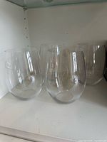 Four Riedel stemless wine glasses on shelf