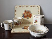 Full lot showing placemats, two-handled cup, single-handled mug, cereal bowl, coin bank