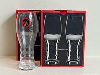 Box front with one loose glass and graphics of pair filled with beverage