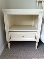 Front view of cream painted bedside cabinet next to wall