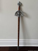 Full view of sword in scabbard leaning against wall