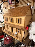 Front angled view of two-storey wood dollhouse on shelf