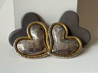 Front view showing both pairs: silver/gold Edouard Rambaud hearts and matte grey hearts