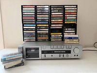 Akai cassette deck, cassette rack filled with tapes and additional loose tapes