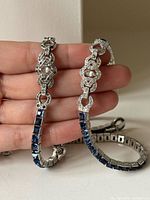 Close view of necklace and bracelet links showing blue square stones and clear rhinestone links