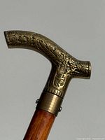 Close-up of ornately embossed brass handle joined to wood shaft