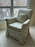 Front view of floral swivel rocker chair showing overall design and pillow