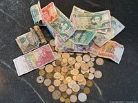 Group shot of banknotes and coins spread on black surface