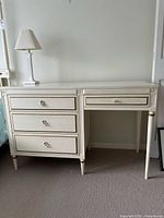 Front view of ivory painted desk showing overall form, drawers, and tapered legs