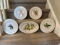 Group shot of five Italian hand-painted vegetable plates and platters on stairs