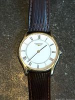 Front view of watch showing dial, gold plated case, brown strap