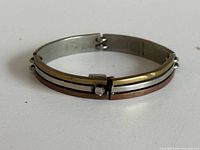 Closed bracelet showing tri-metal bands and clasp front