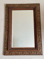 Full view of rectangular mirror showing carved wooden frame and beveled glass