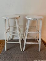 Two white painted wooden stools front view