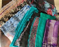 Group view of all eight pashmina shawls and scarves folded on table