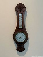 Front view of carved walnut barometer and thermometer