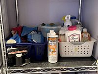 Full view of shelf section showing assorted bottles, cloths, gloves, brushes, caddy, bowls and baskets