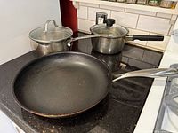 Frying pan, both saucepans and lids on stovetop