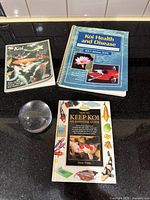 Three koi care books and clear paperweight on countertop