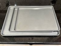 Three nesting gray nonstick baking sheets on counter