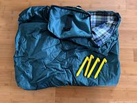 Folded green picnic blanket, carry pouch and four yellow stakes