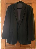 Front view of black blazer on hanger showing overall style, lapel, pockets, buttons