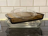 Stacked view of amber rectangular pan, clear rectangular pan and clear oval lid