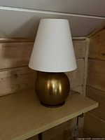 Front view of spherical brushed gold lamp with white shade