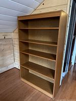 front view of tall wood veneer bookcase with five shelves