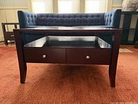 Front view of dark wood coffee table showing drawers, shelf, and leg design