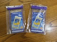 Two packaged waterproof smartphone pouches with purple tops displayed on table