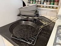 Full lot showing grill skillet, stacked baking pans, rack and grill basket