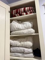 Cabinet shelves with six folded bath towels in striped red-white, solid white and light grey