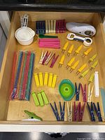 Drawer showing all items laid flat: measuring cups/spoons, straws, clips, corn holders, funnel, jar opener