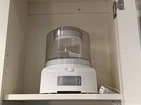 Front view of Cuisinart ice cream maker showing base, clear mixing chamber and cord