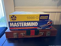 Stacked view of puzzle, Mastermind box, and backgammon case