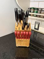 Front view showing Miracle Blade logo, block, black-handled knives and eight red-handled steak knives