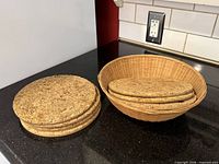 Stack of cork trivets beside wicker basket holding additional trivets