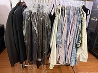 Full rack with suits in garment bags and row of shirts