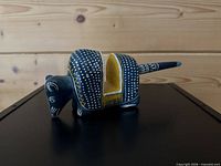 Left side profile of blue and yellow dotted wooden armadillo figurine